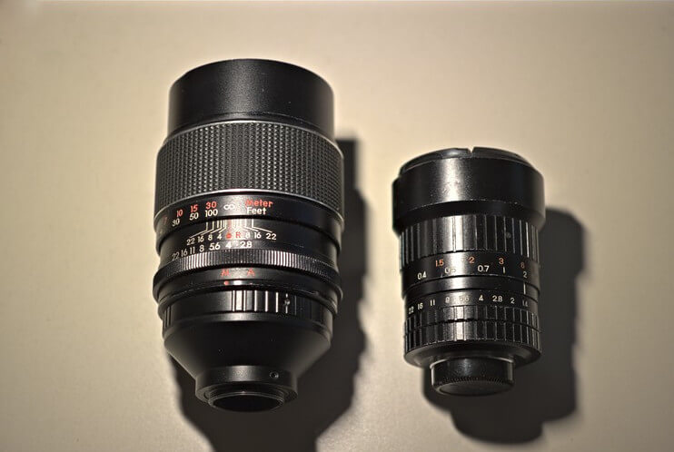 Photo of a compact C-mount lens next to a much larger M42, illustrating the size difference.